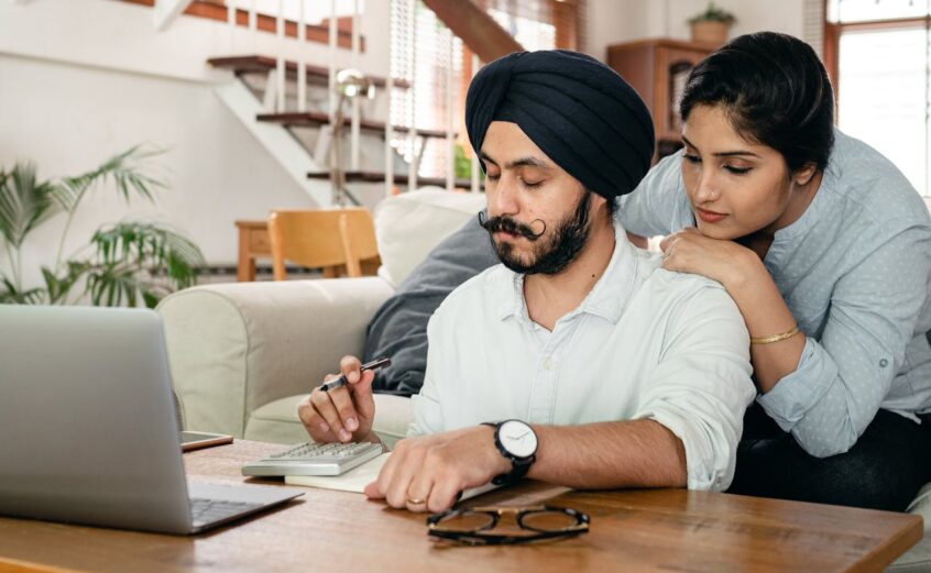 Cheerful couple counting with calculator and writing notes