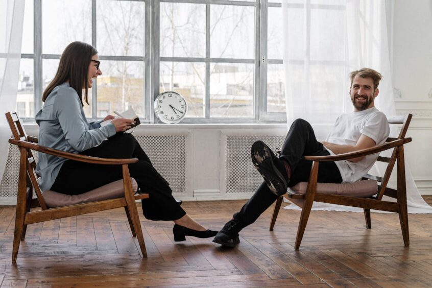 Woman and Man Sitting on Brown Wooden Chairs