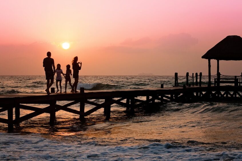 People standing on dock during sunset