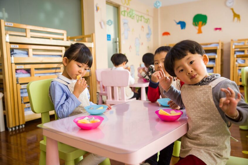 Three toddlers eating at pink table